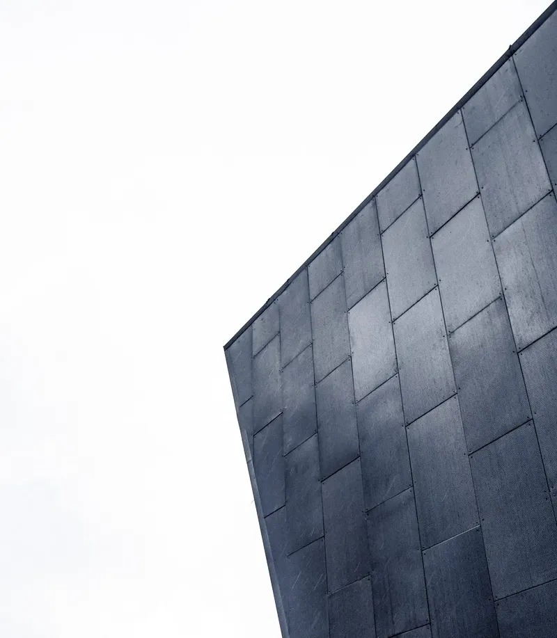 Dark tiled facade against a white sky